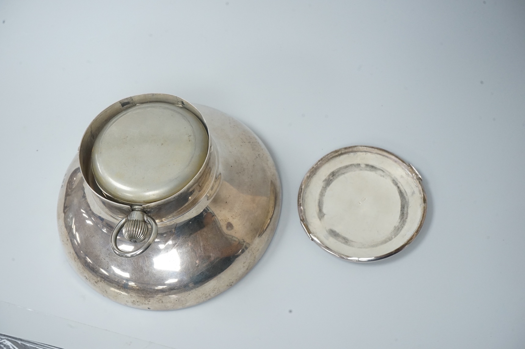 An Edwardian silver circular inkwell, the hinged cover inset with an 8-day open faced pocket watch, with Roman dial and subsidiary seconds, makers mark rubbed, Saunders & Shepherd?, Birmingham, 1907, diameter of the base